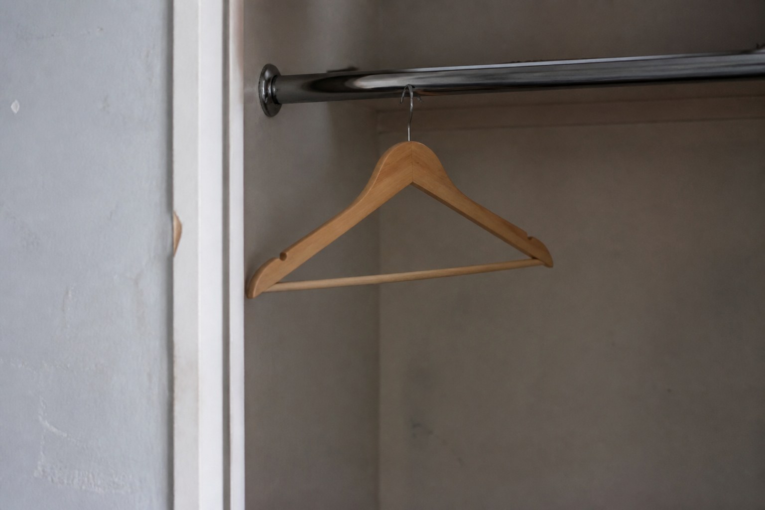 An almost empty clothes rail with a single wooden hanger on it