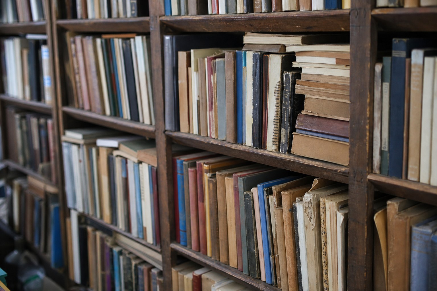 A secondhand bookshop shelf of mixed paperbacks with worn unreadable spines