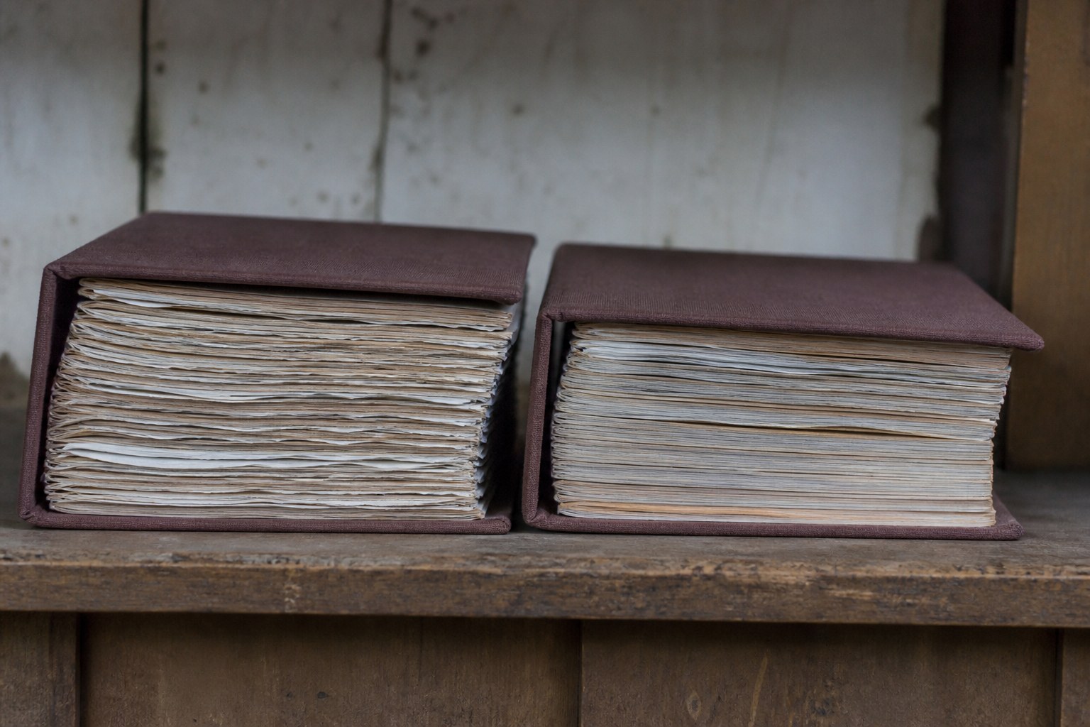 Two identical bound registers side by side on a shelf, one noticeably fuller