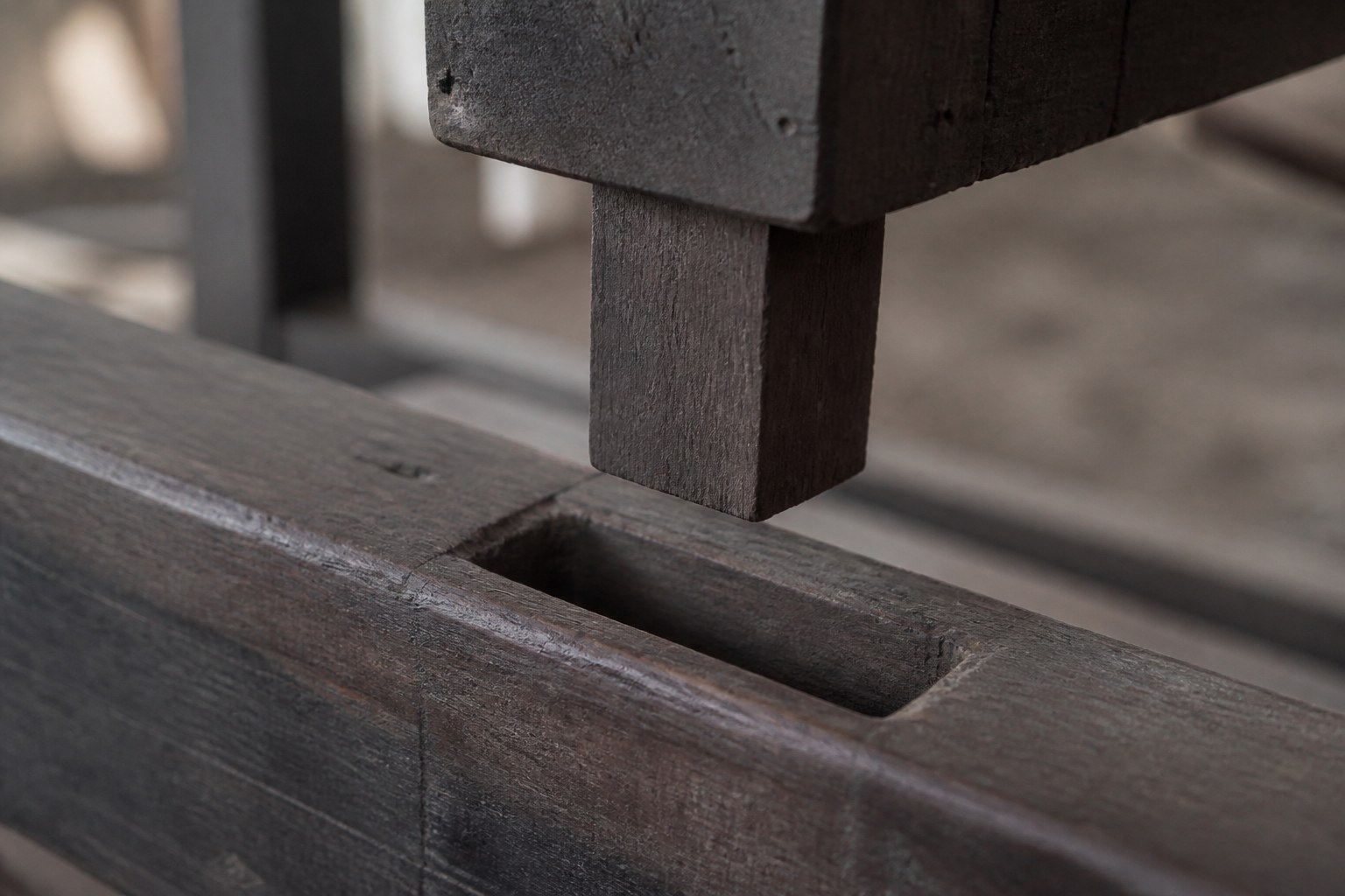 A mortise and tenon joint in dark timber, the tenon standing just clear of its mortise
