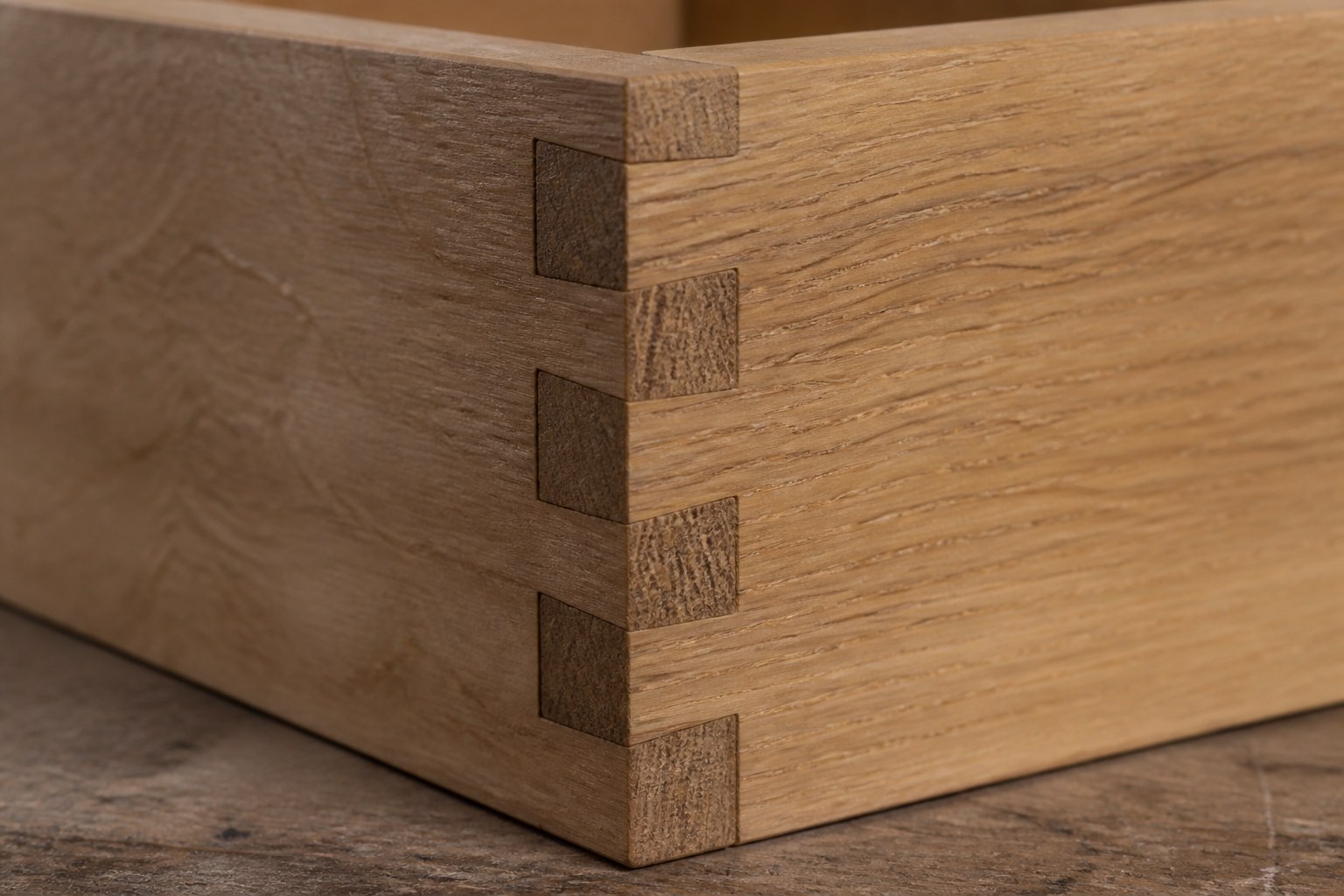 A wooden box joint with square fingers interlocking at a corner