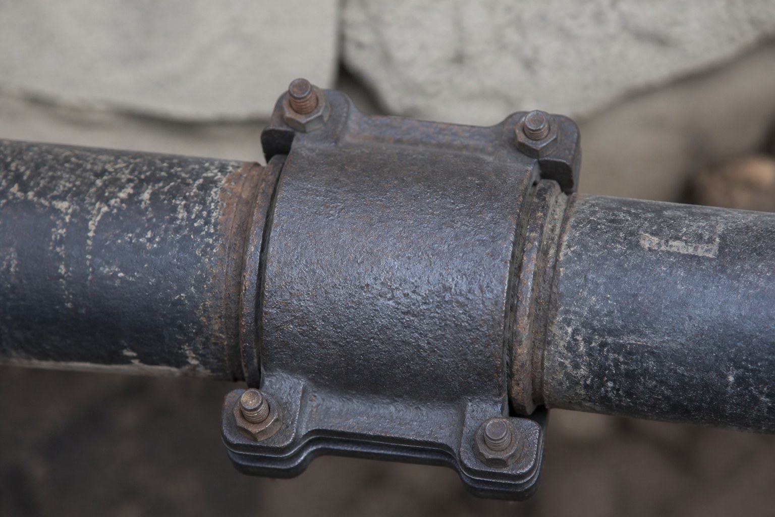 A cast iron pipe collar clamped over the joint between two pipes