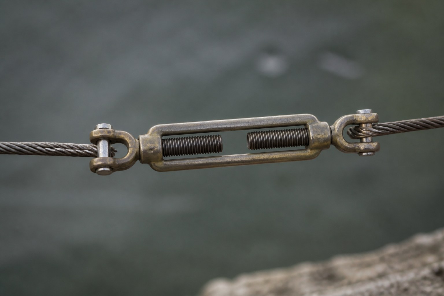A bronze turnbuckle taking up the slack between two wire ends