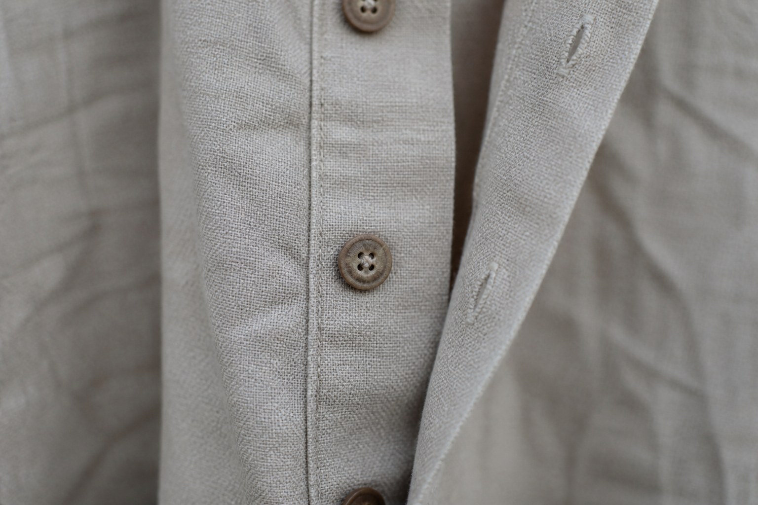 A buttoned placket on a heavy linen shirt, the buttonholes hand worked