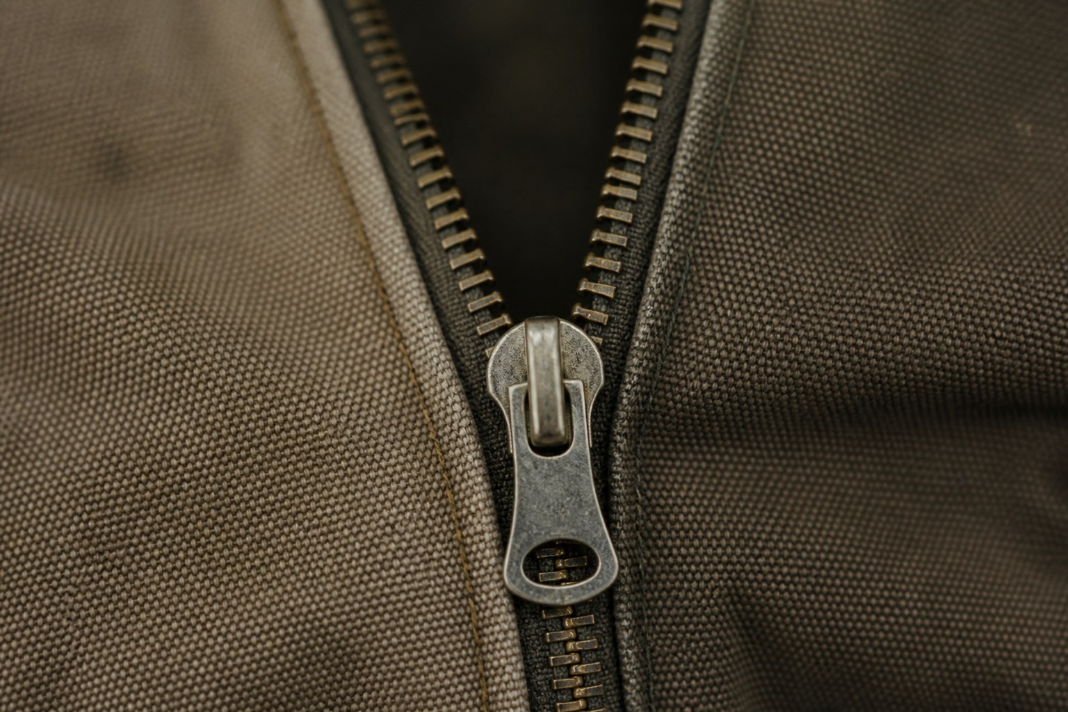 A metal zip half closed across two panels of canvas