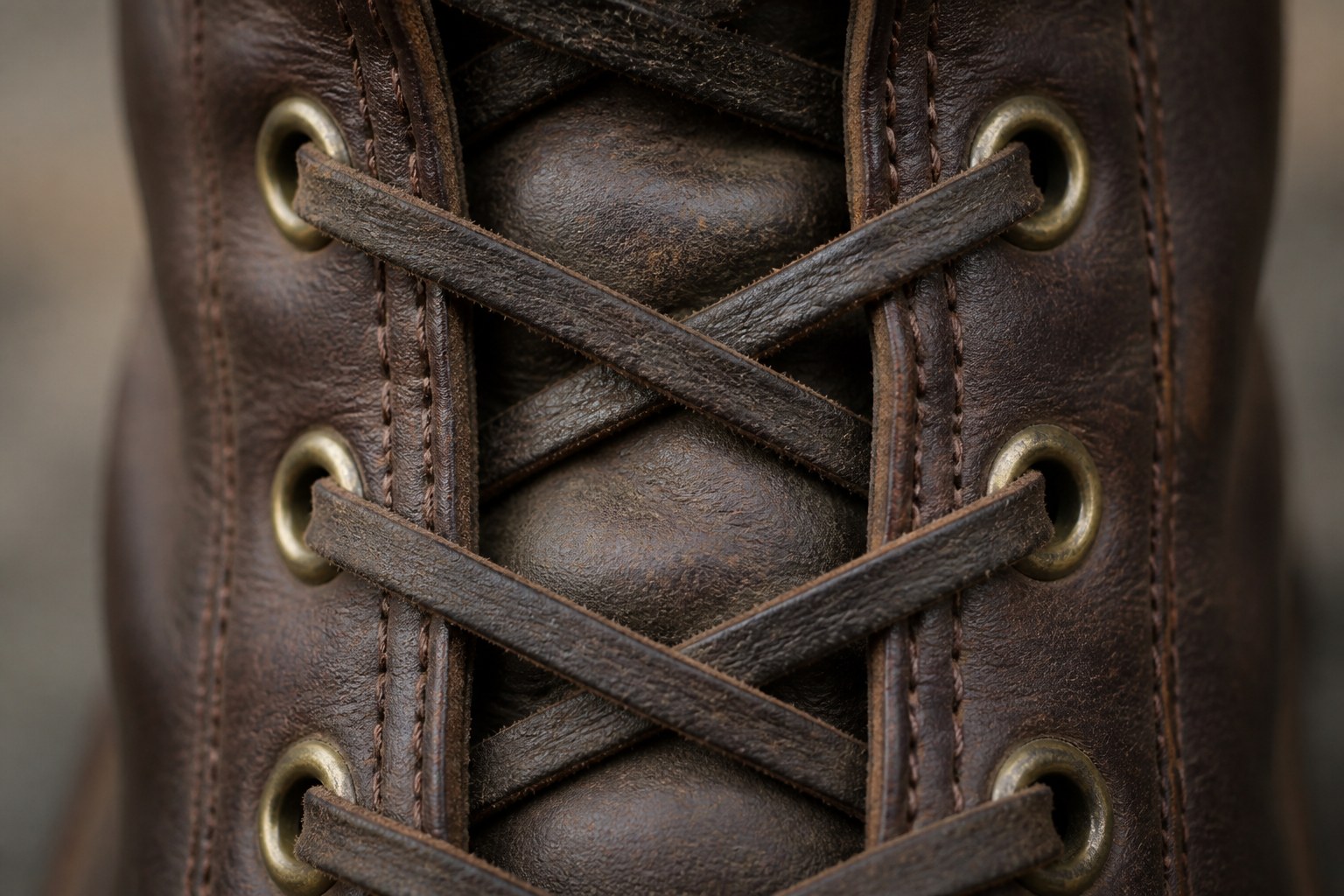Leather boot laces crossed through brass eyelets and pulled tight