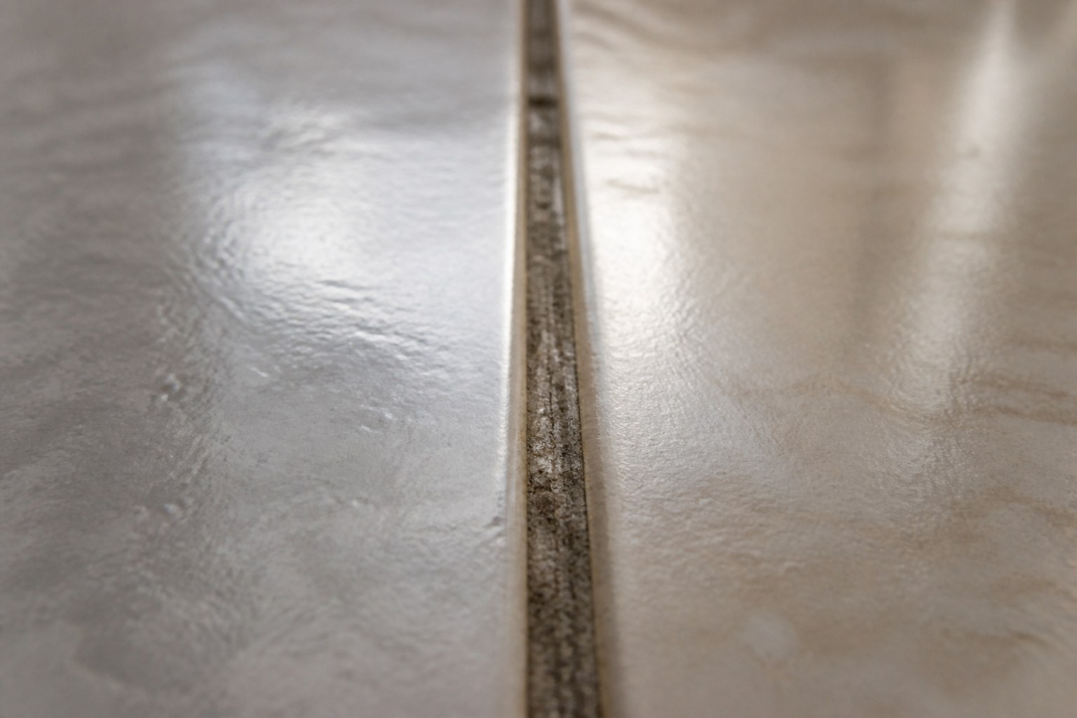 A grout line running between two glazed floor tiles