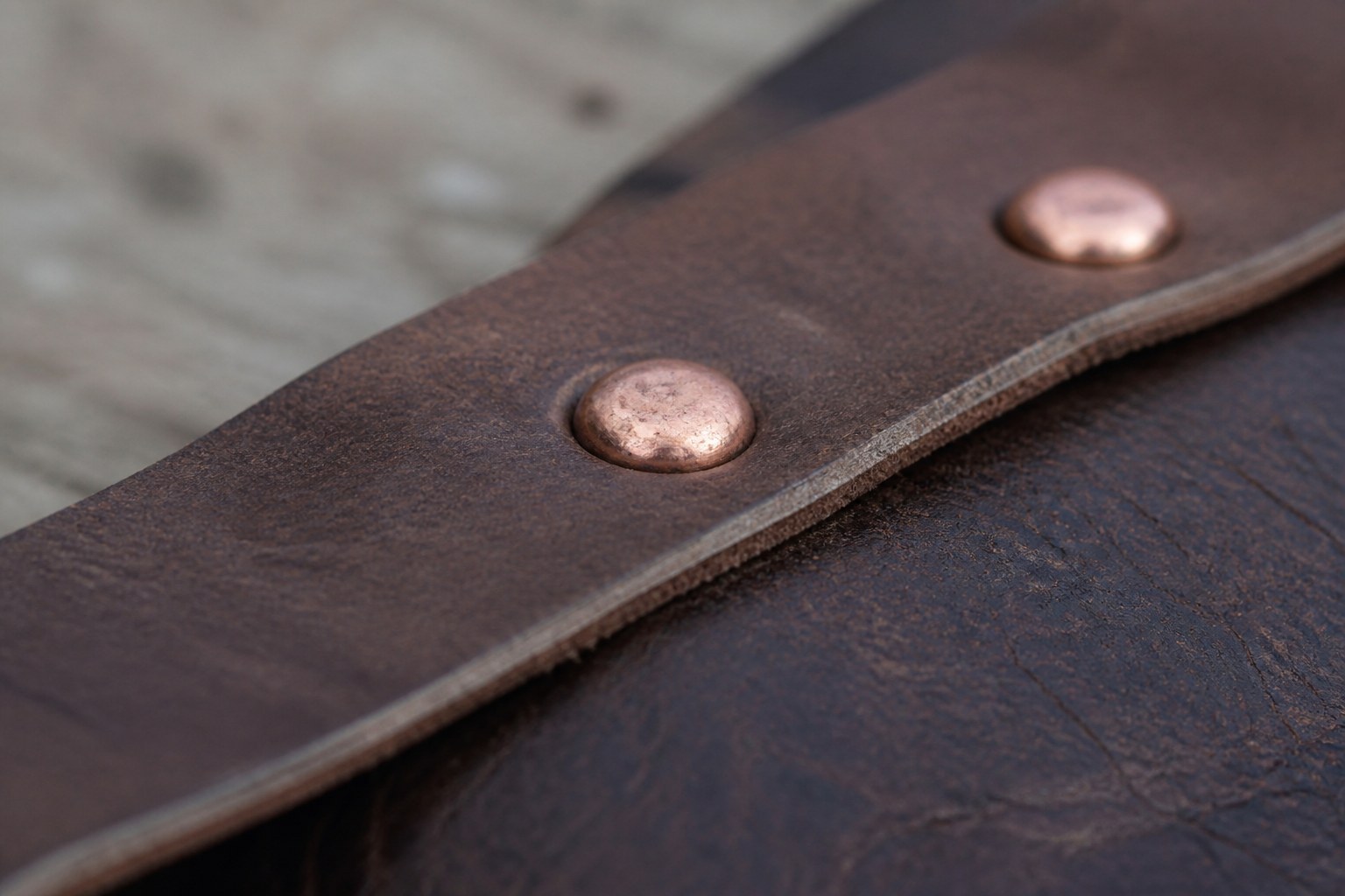 Copper rivets set through two overlapping pieces of leather
