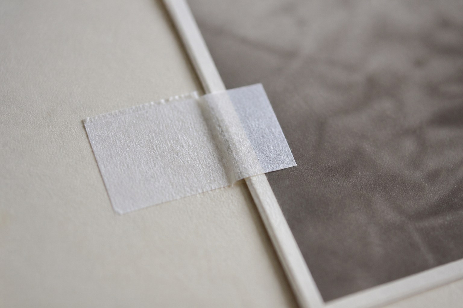 A paper hinge holding a print to its mount board