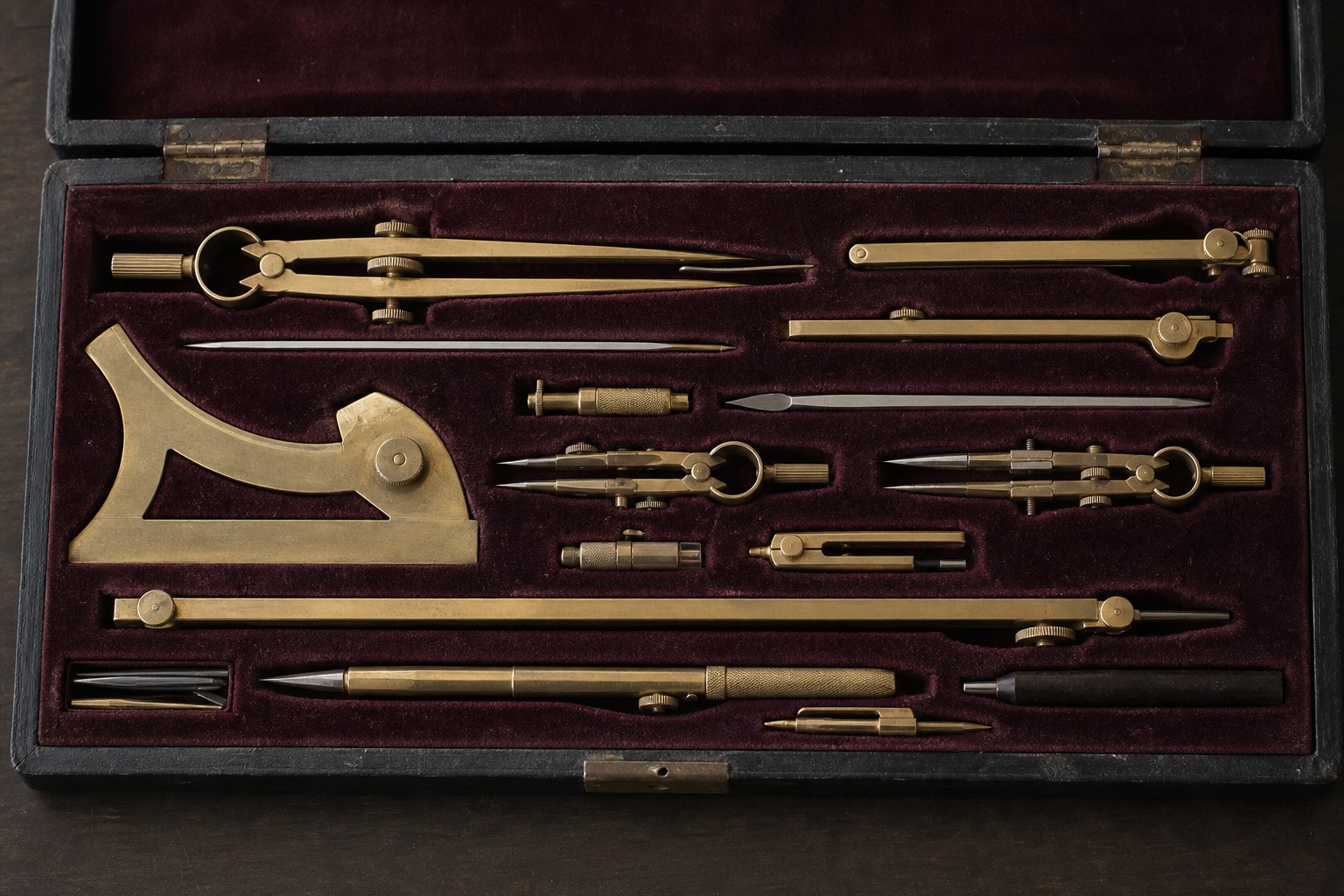 A complete set of brass drafting instruments seated in the fitted recesses of a velvet lined case