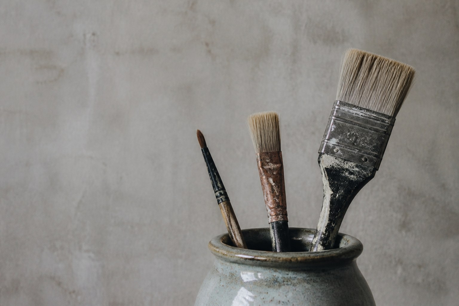 Paintbrushes of different sizes standing together in a glazed jar
