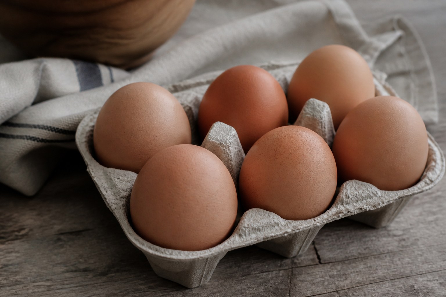 Brown eggs sitting in a moulded tray on a kitchen table