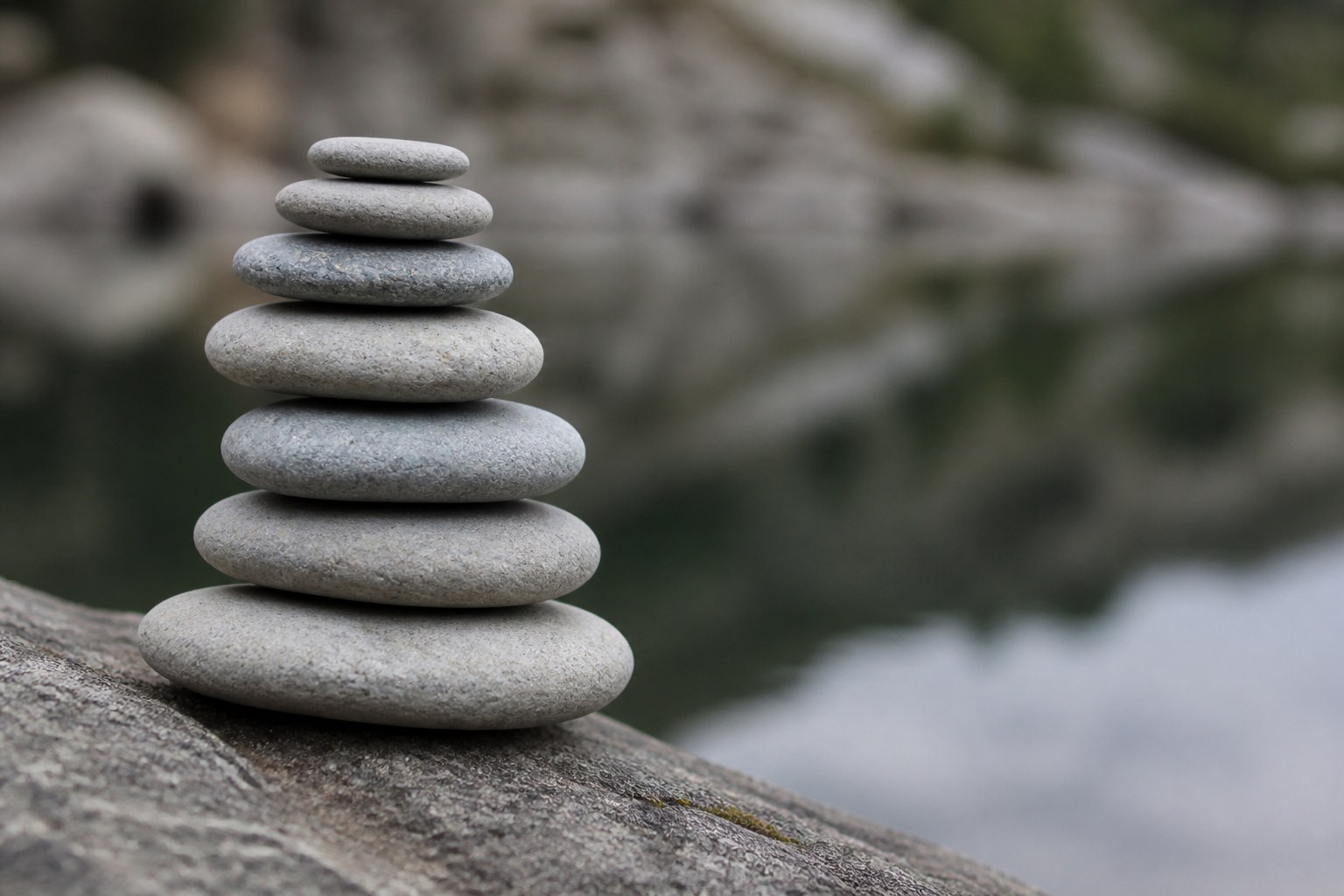 Flat stones stacked into a small cairn on rock beside still water