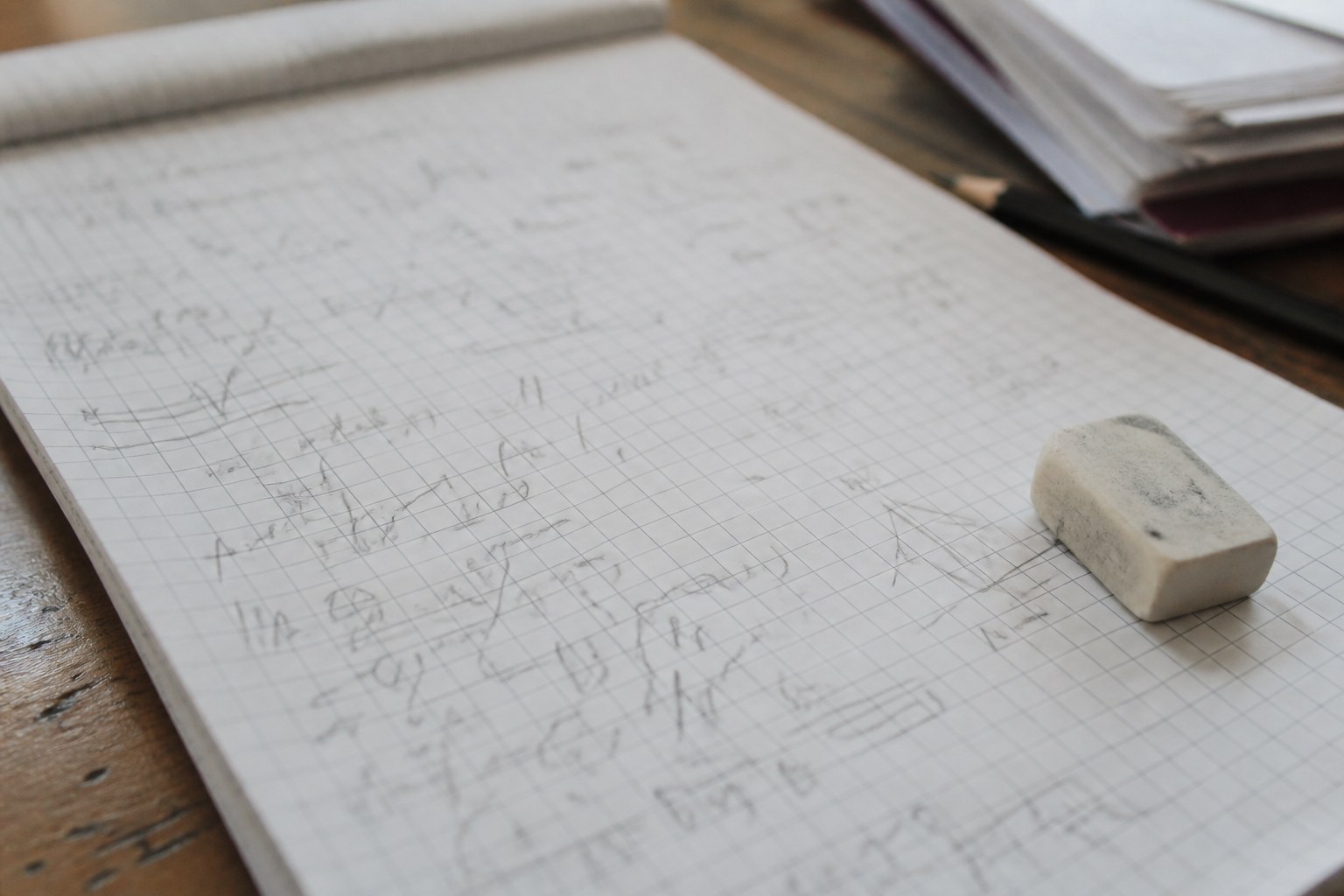 A worked sum in pencil on squared paper with a rubber beside it