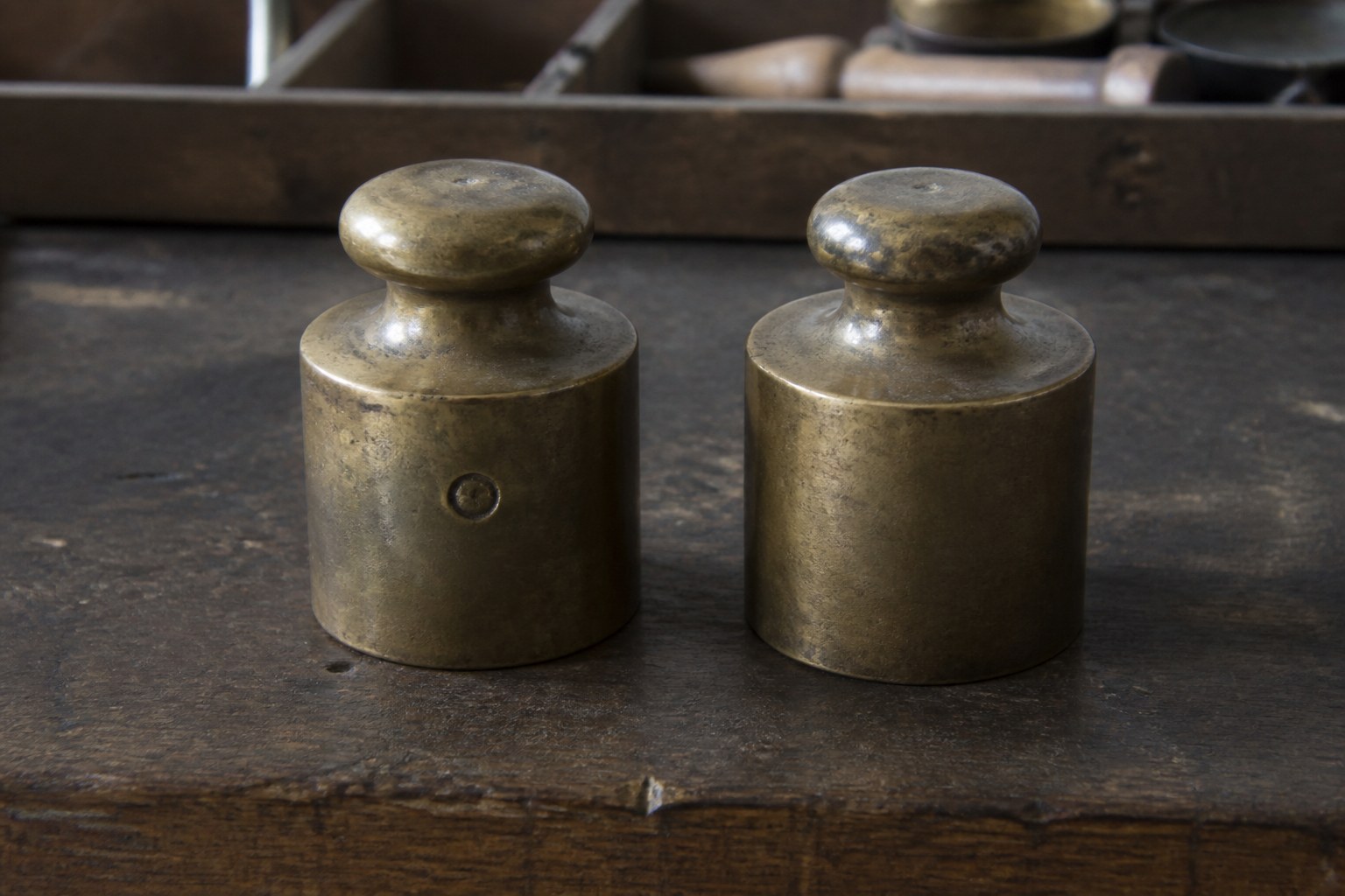 Two identical brass weights on a bench, one stamped and one blank