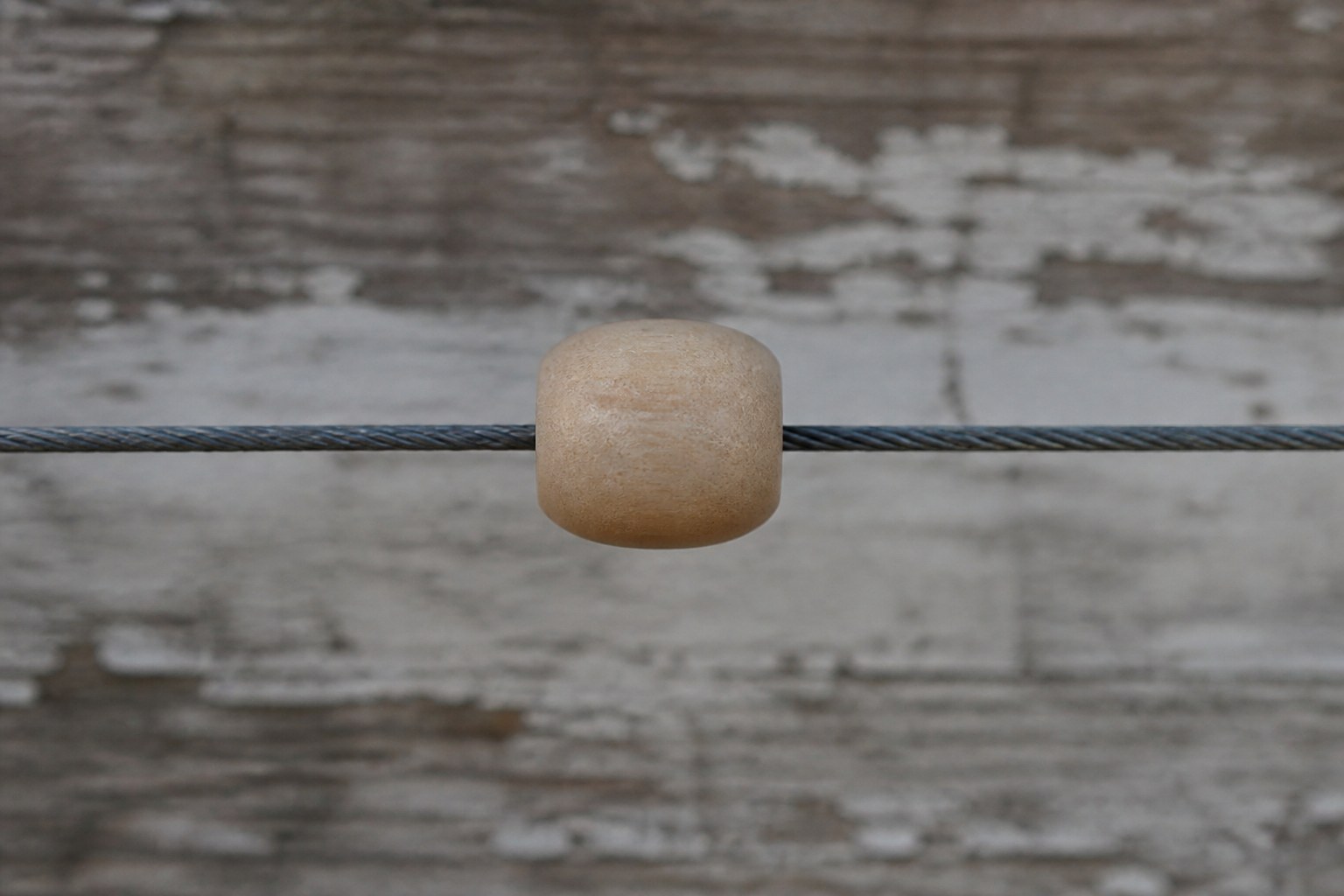 A single turned wooden counting bead threaded on a taut horizontal wire