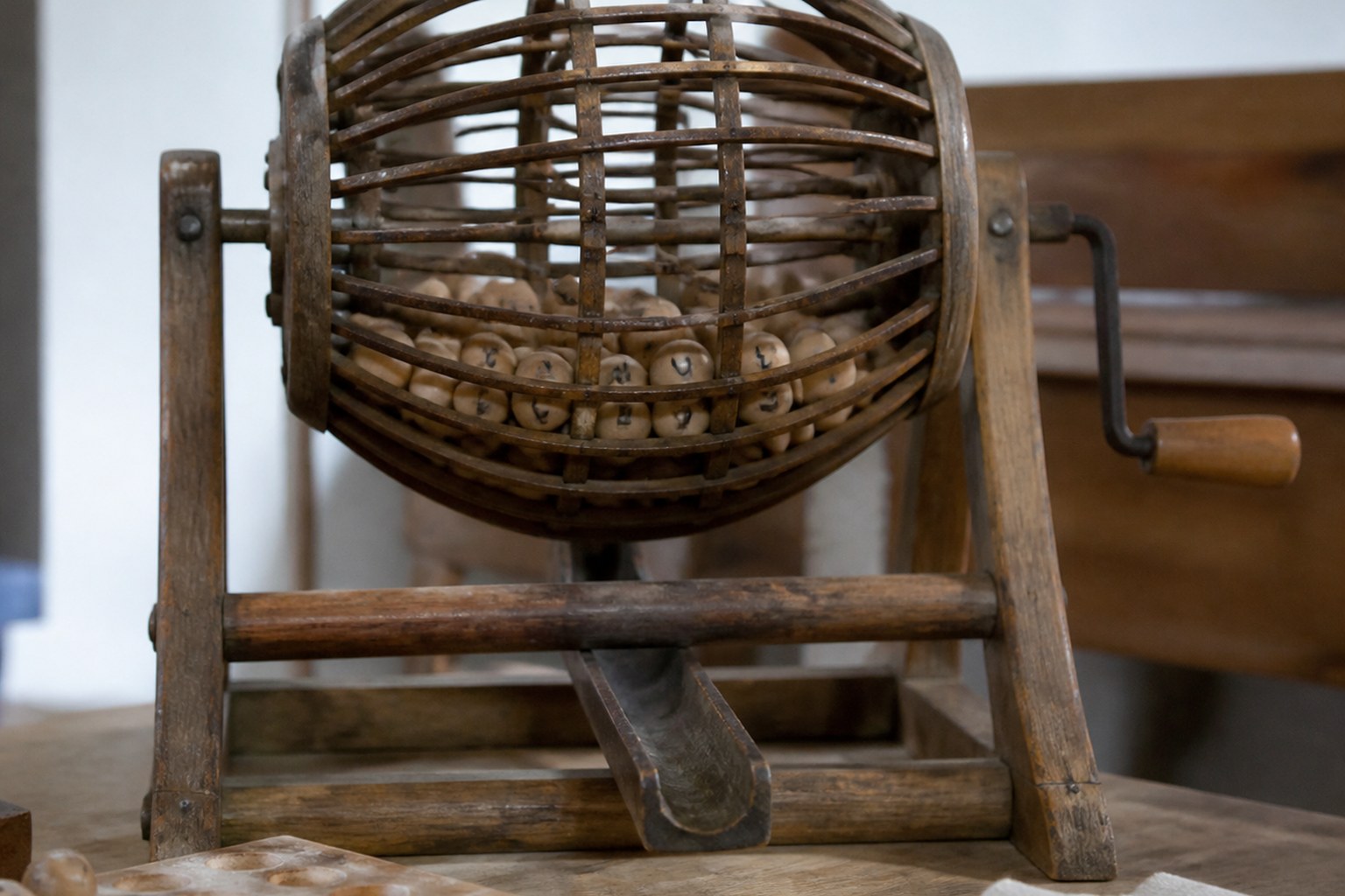 A hand-cranked wooden bingo cage holding lettered wooden balls