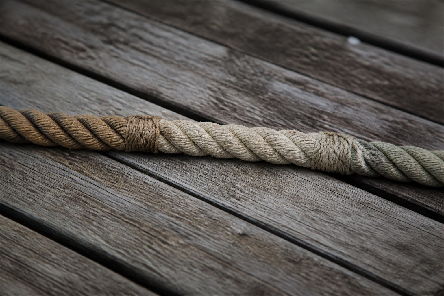 Three lengths of rope spliced end to end into one continuous line lying on weathered planking