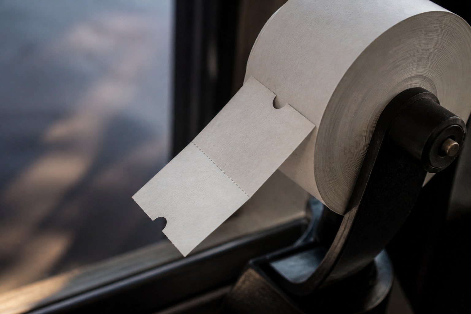 A single ticket torn from a long paper roll, the roll still on its spindle
