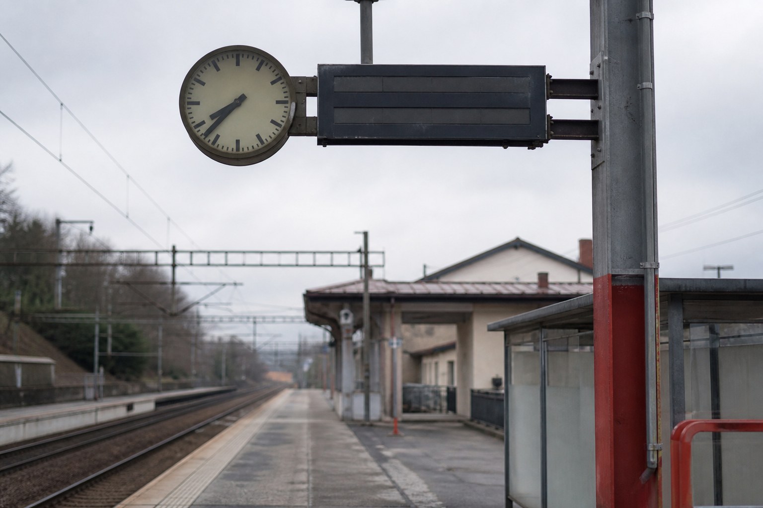 A large public station clock and date display above an empty platform